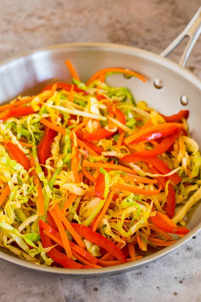 Diese Yakisoba Nudeln sind zarte, gebratene Nudeln, die in einer herzhaften Sauce mit Hähnchen und Gemüse zubereitet werden. Stir fried vegetables in a skillet.