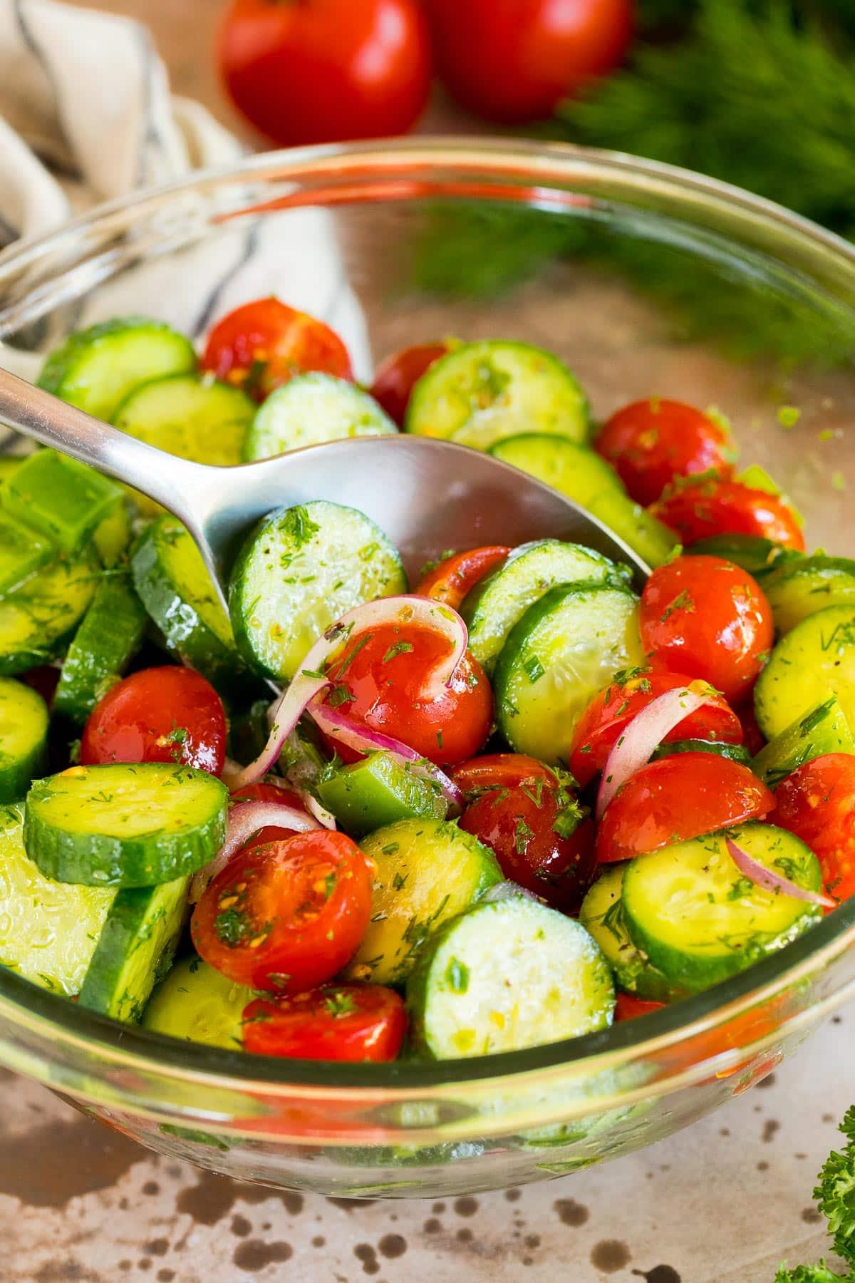 Gurken-Tomaten-Salat 5 Ein Löffel serviert eine Portion Gurken-Tomaten-Salat.