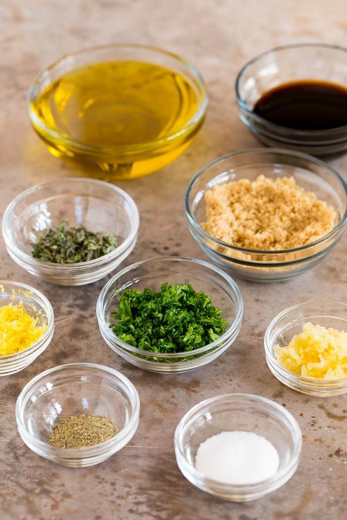 Schüsseln mit frischen Zutaten wie Knoblauch, Kräutern, Olivenöl und Sojasauce, die für die Zubereitung der Marinade bereitstehen.
