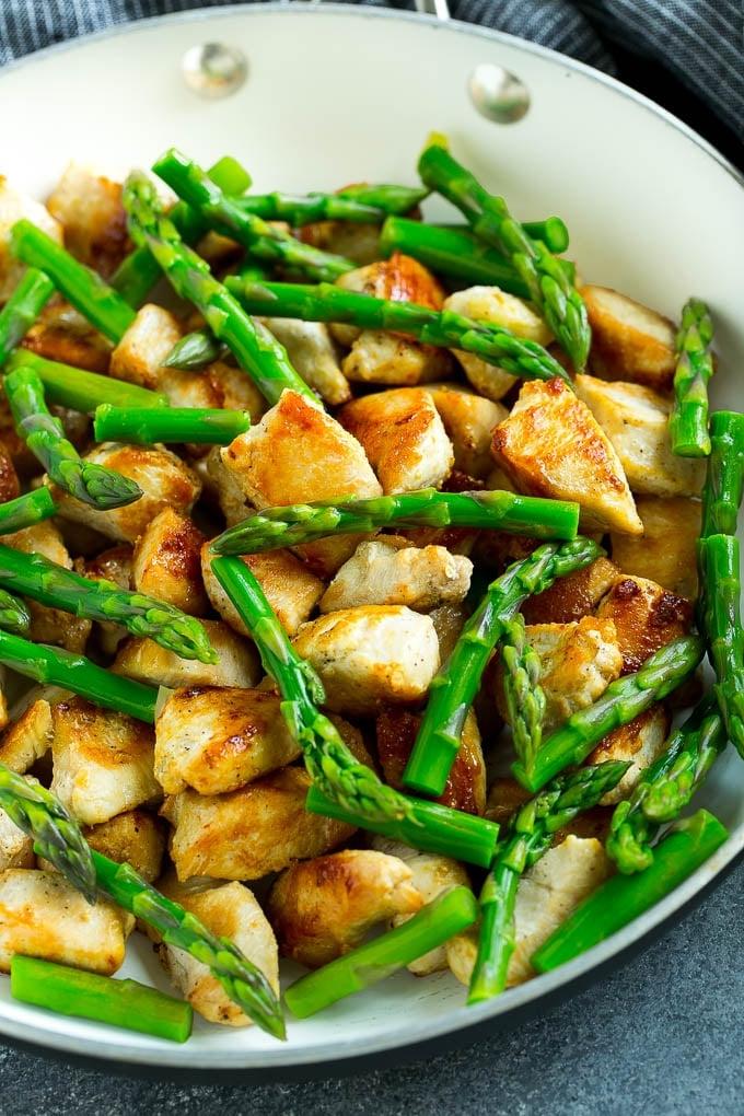 Eine Pfanne mit angebratenem Hähnchen und Spargel.