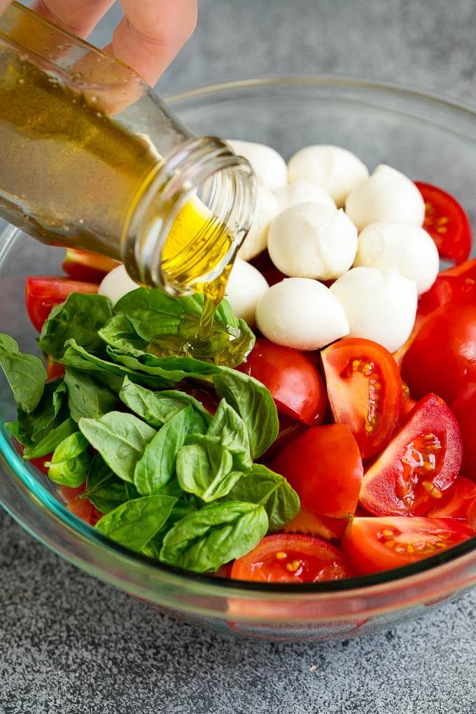 Caprese Salad Recipe | Tomato Salad #salad #tomato #mozzarella #cheese #basil #caprese #summer #ahurt Olivenöl wird über Tomaten, Mozzarella und Basilikumblätter gegossen.
