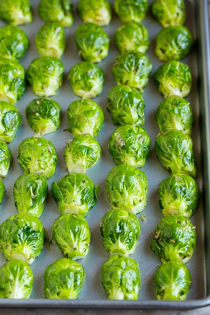 Dieser knusprige Rosenkohl ist mit Olivenöl, Knoblauch und Gewürzen überzogen und wird bei hoher Hitze geröstet, bis er zart und goldbraun ist. Rosenkohlröschen auf einem Backblech, mit der Schnittfläche nach unten ausgerichtet – die Basis für ultimative Knusprigkeit.