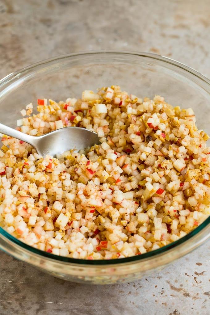 Dieses Charoset Rezept ist eine Mischung aus Äpfeln, Walnüssen und Honig, die zusammen eine süße Paste bilden, die ein wesentlicher Bestandteil jeder Passah-Mahlzeit ist. Eine Rührschüssel gefüllt mit gewürfelten Äpfeln, Zimt und Süßungsmittel.