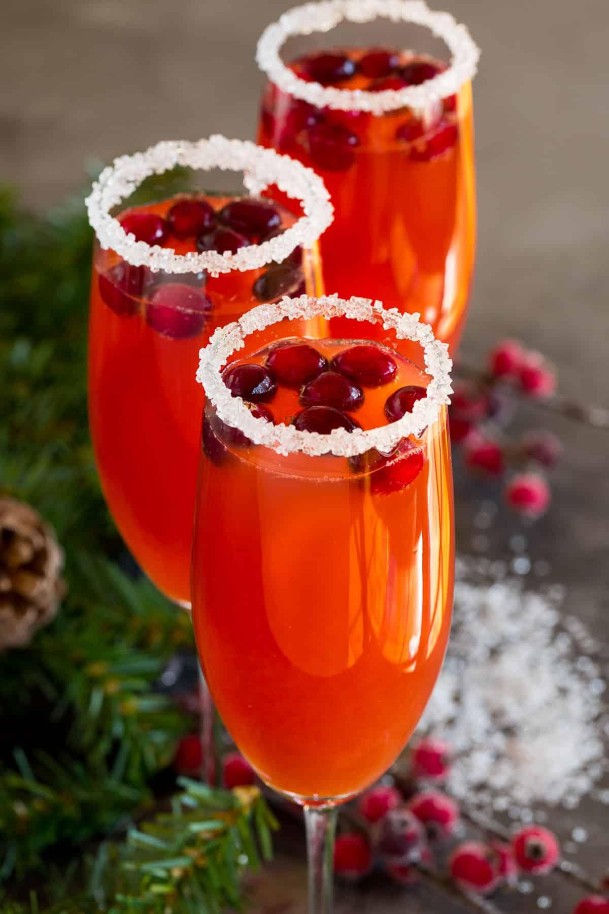 Preiselbeer-Mimosa 5 Gläser mit Zuckerrand, Getränk und Garnitur.