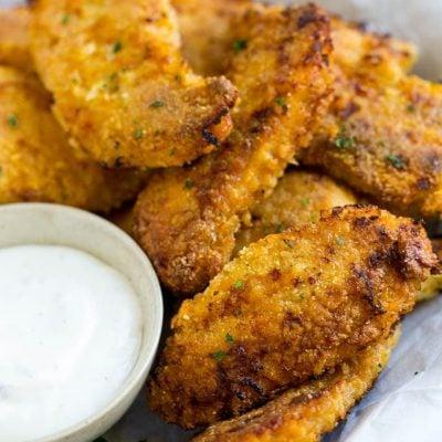 **Gebackenes Fried Chicken** 2 Knusprige gebackene Hähnchenfinger auf einem Teller mit Ranch-Dip.