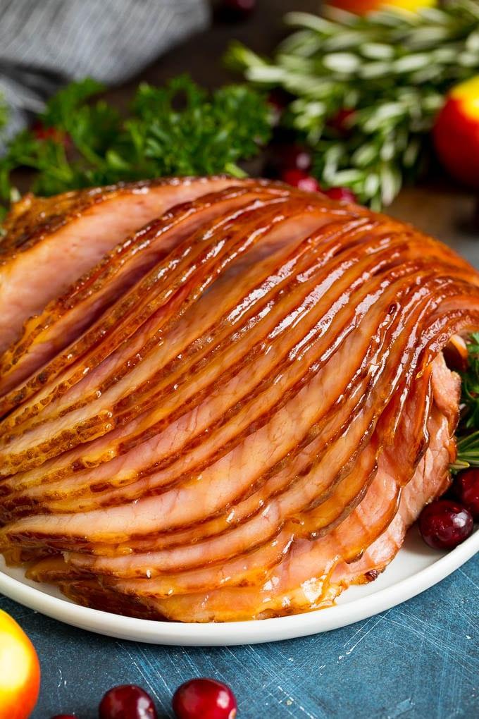 Dieser Instant Pot Schinken ist ein Spiral-Schinken, der mit einer 3-Zutaten-Glasur überzogen und dann im Schnellkochtopf zu zarter Perfektion gegart wird. Geschnittener Schinken auf einem Teller, garniert mit Preiselbeeren.