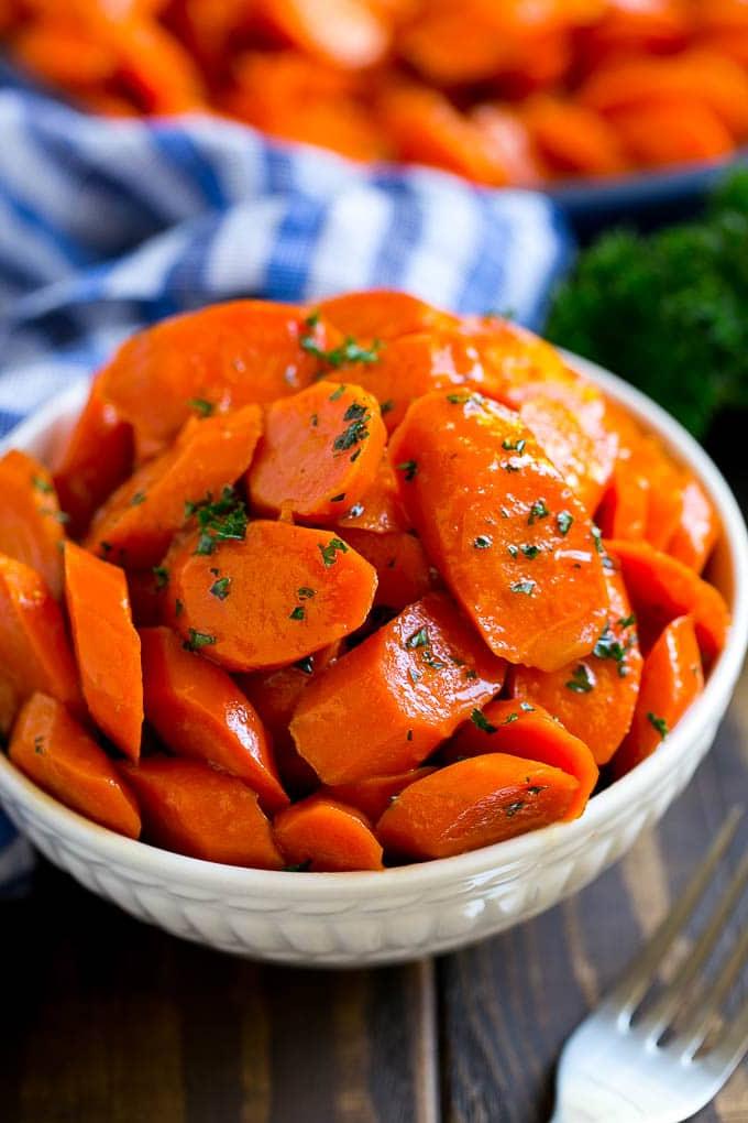 Rezept für Glasierte Karotten | Brauner Zucker Karotten | Karottenbeilage #Karotten #braunerZucker #Beilage #glutenfrei #Thanksgiving #Herbst #Abendessen #ahurt Eine Schüssel glasierter Karotten, garniert mit Petersilie.