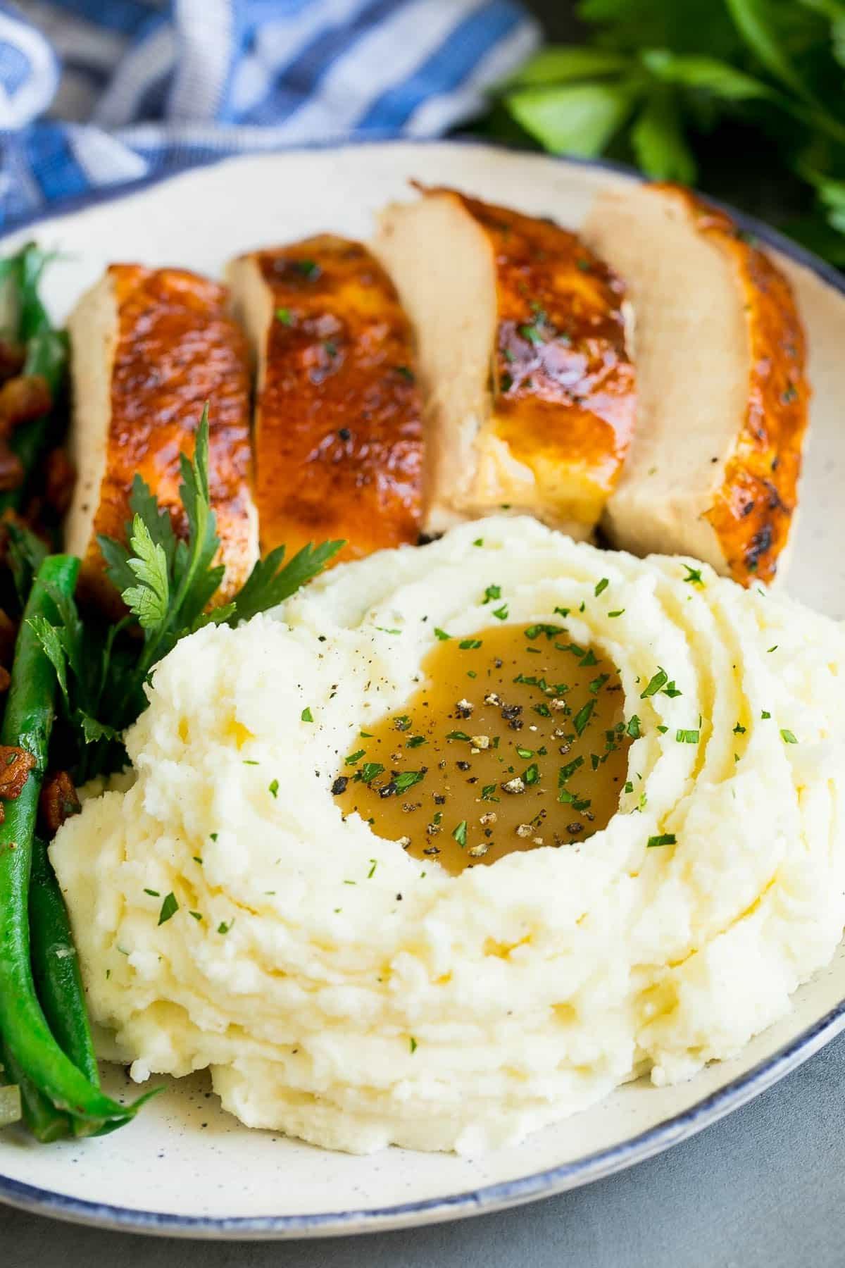 Kartoffelpüree aus dem Schongarer 6 Slow Cooker Kartoffelpüree auf einem Teller mit Truthahn, grünen Bohnen und Soße.