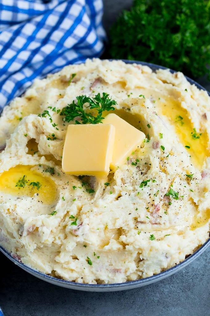 Diese Kartoffelpüree aus roten Kartoffeln sind zarte Kartoffeln, kombiniert mit Knoblauch, Butter und Gewürzen, um eine einfache und doch völlig befriedigende Beilage zu schaffen. Eine Schüssel mit rotem Kartoffelpüree mit Butter und gehackten Kräutern.