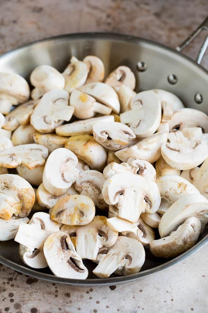 Rohe geschnittene Champignons in einer Pfanne, bereit zum Sautieren.