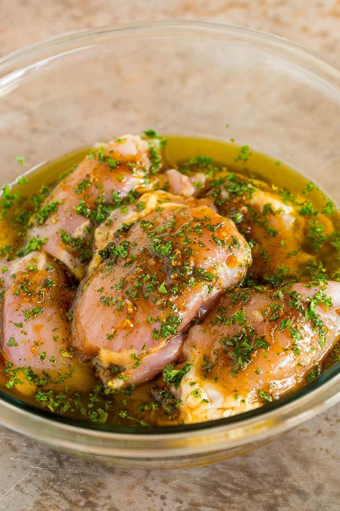 Rohe Hähnchenschenkel in einer Schüssel voller duftender Marinade, bereit für den Kühlschrank.