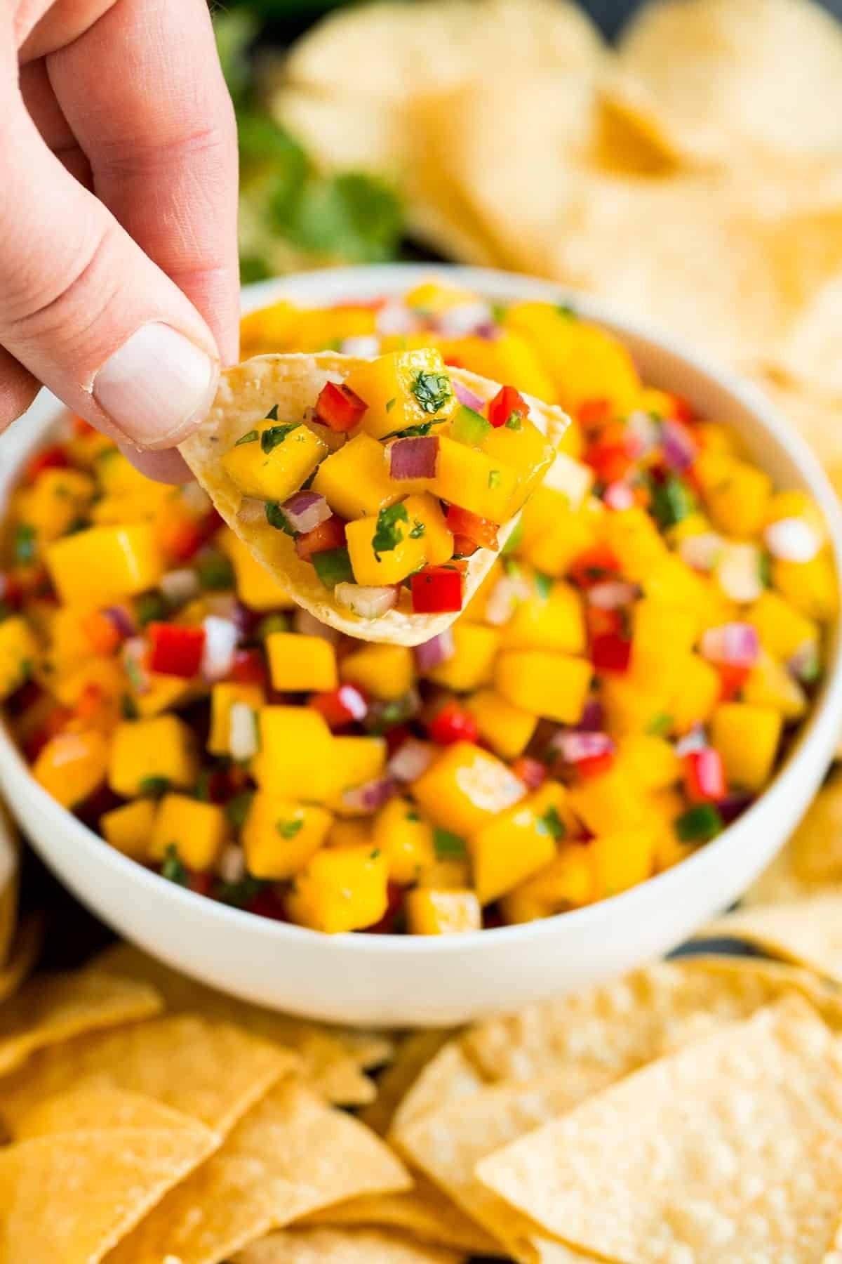 Mango Salsa Rezept 6 Eine Hand, die einen Tortilla-Chip mit Mango Salsa hält.