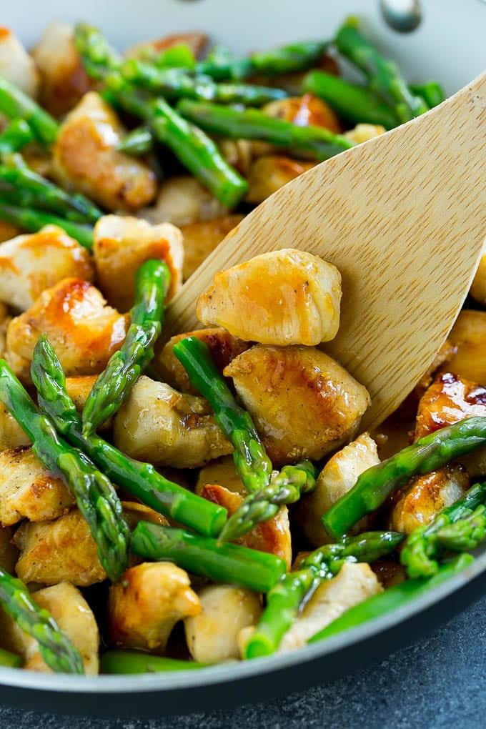 Hähnchen-Spargel-Wok in einer Pfanne mit einem Servierlöffel.