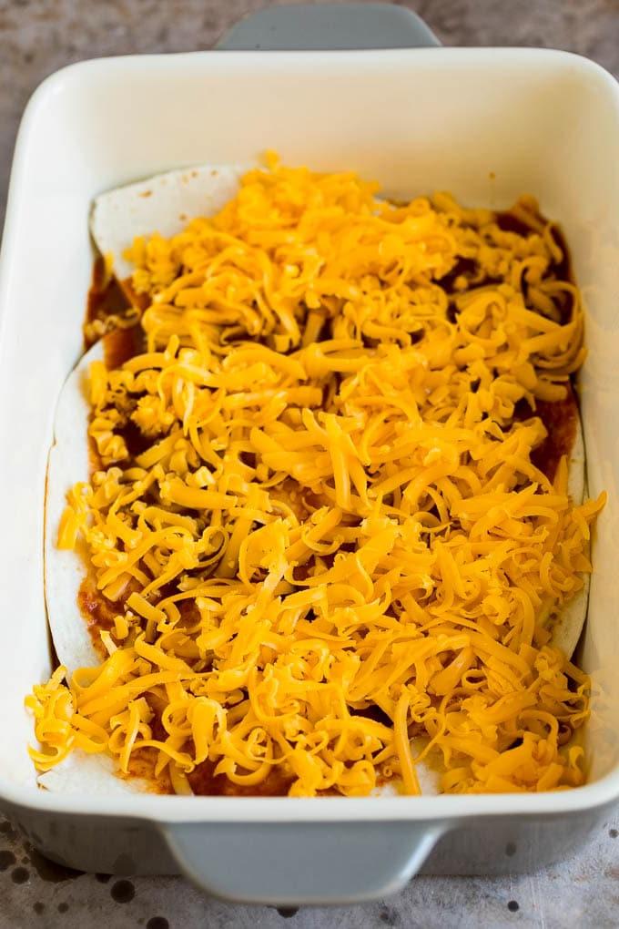 Schichten von Tortillas, Käse und Enchilada-Sauce in einer Auflaufform.