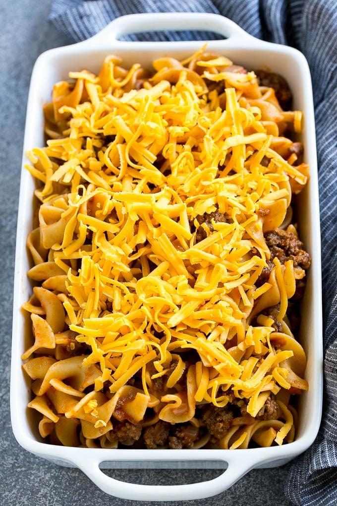 Eine Pfanne mit Hackfleisch und Eiernudeln in Tomatensoße, mit geriebenem Cheddar-Käse belegt.