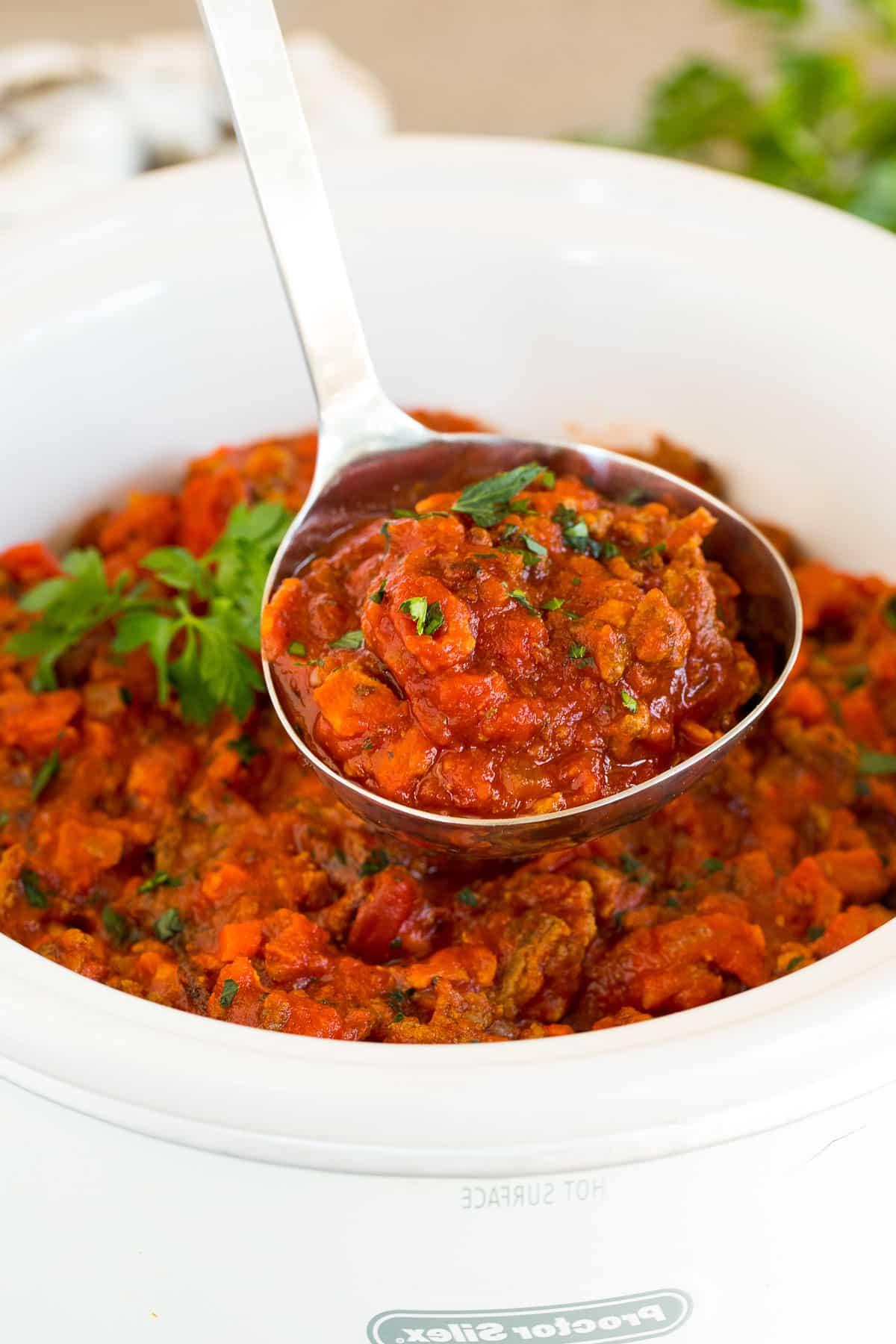 Schongarer-Bolognesesoße 6 Eine Kelle hält eine Portion Slow Cooker Bolognese Sauce.