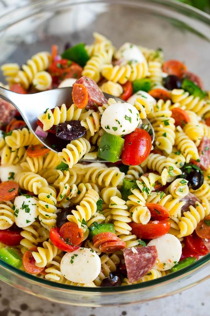 Italienischer Nudelsalat | Nudelsalat Rezept #Nudeln #Salat #Nudelsalat #Peperoni #Salami #Oliven #Käse #Beilage #Abendessen Ein Servierlöffel in einer Schüssel Nudelsalat nach italienischer Art.