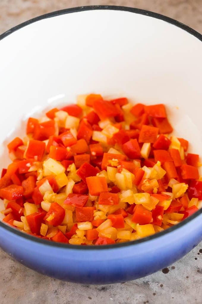 Sanft angebratene Zwiebeln und Paprika in einem großen Kochtopf, die Basis für das Chili.