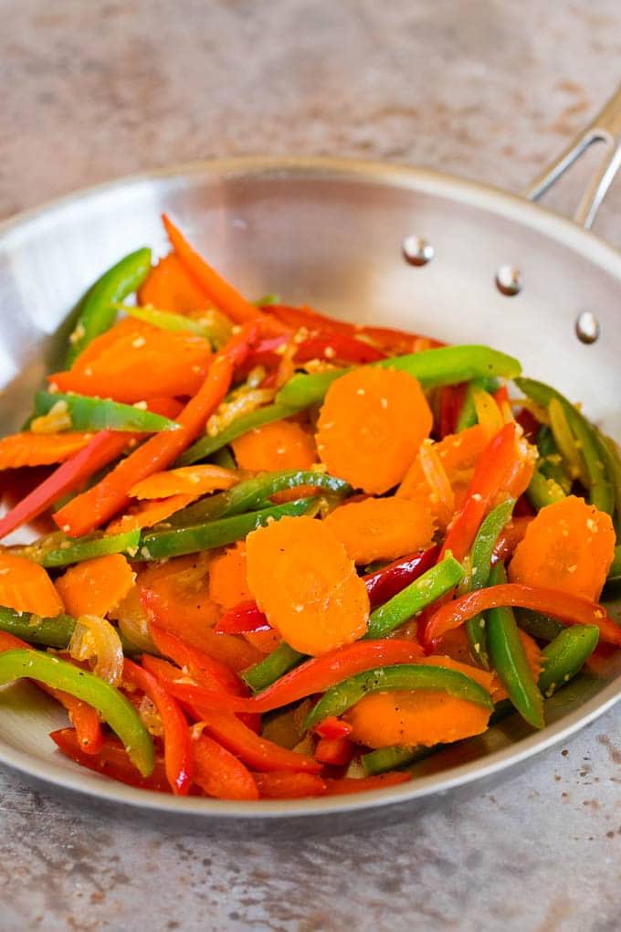 Angebratene Karotten und Paprika in einer Pfanne.