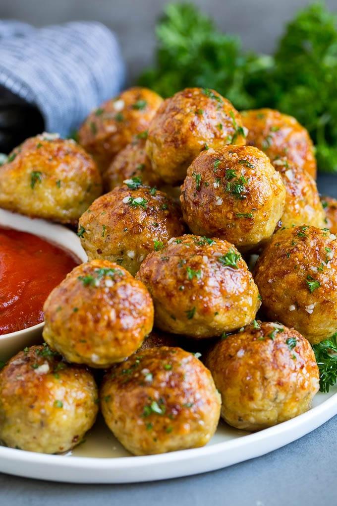 Rezept für Hähnchenfrikadellen | Gebackene Fleischbällchen #hähnchen #fleischbällchen #abendessen #abendessenimzoo #wohlfühlessen Ein Servierteller mit Hähnchenfrikadellen, serviert mit Marinara-Sauce.