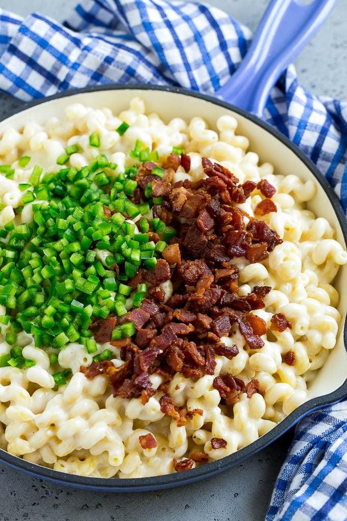 Makkaroni und Käse in einer Pfanne, belegt mit Bacon und gewürfelten Jalapeños.