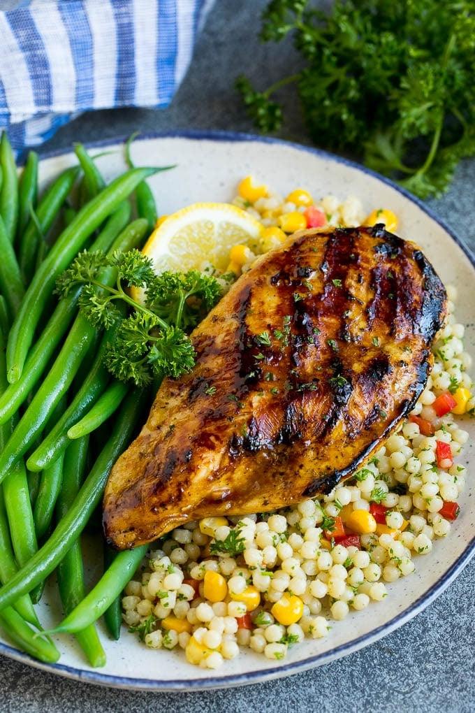 Gegrilltes Hähnchen, gewürzt mit Hähnchenmarinade, serviert mit Couscous und grünen Bohnen.