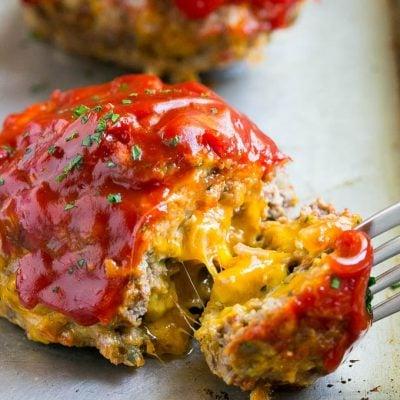 Ein Cheeseburger Hackbraten, von dem ein Stück mit einer Gabel abgenommen wird.