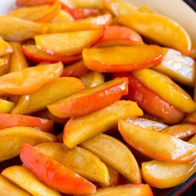 Rezept für gebratene Äpfel 2 Südstaaten-inspirierte gebratene Äpfel, bedeckt mit Butter, Zimt und Zucker in einer Pfanne.