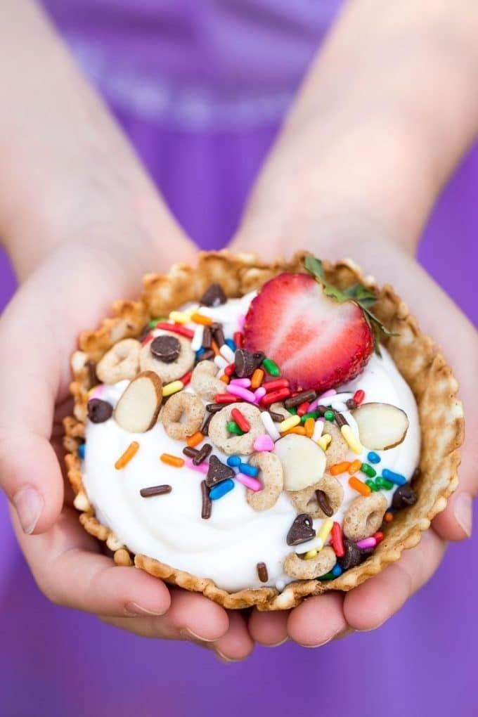Kinderhände halten einen Frühstücks-Sundae.