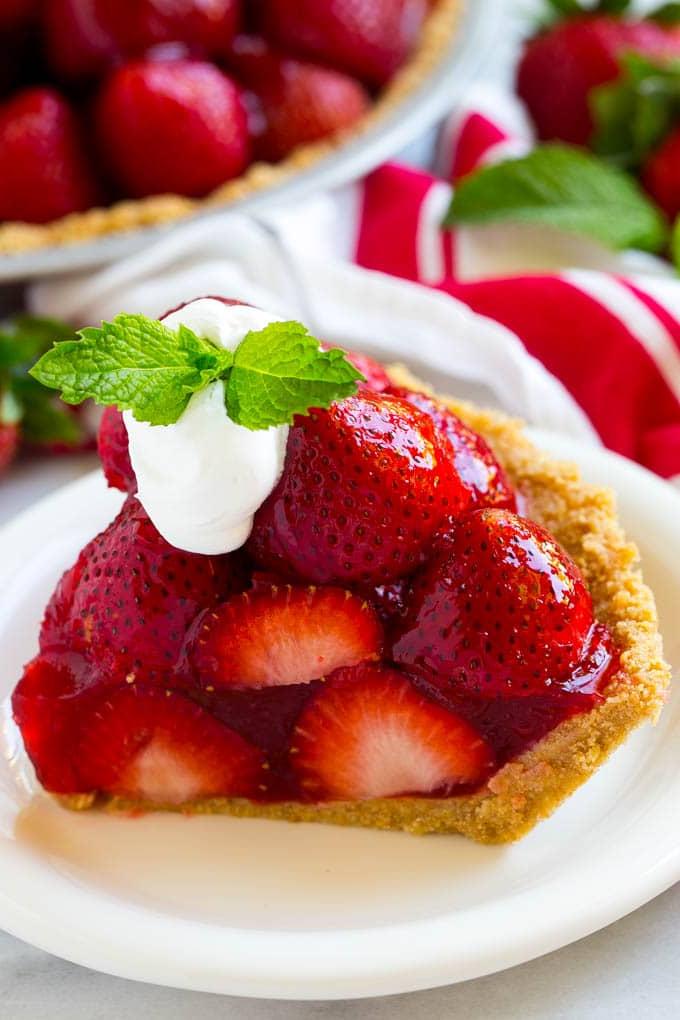 No-Bake Erdbeerkuchen Rezept | Frischer Erdbeerkuchen | Erdbeerkuchen Rezept | No-Bake Kuchen Rezept #erdbeere #erdbeerkuchen #ohnebacken #nobakekuchen #dessert #ahurt Ein Stück No-Bake frischer Erdbeerkuchen mit Schlagsahne obenauf.