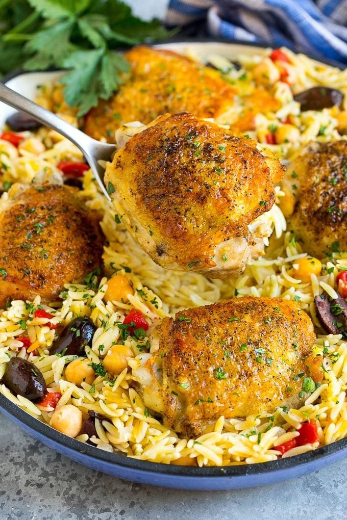 A spoon serving up a portion of Mediterranean chicken thighs.