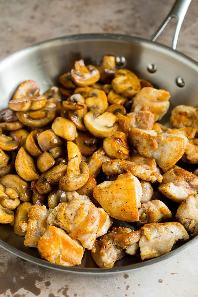 Gekochtes Hähnchen und sautierte Champignons zusammen in einer Pfanne, perfekt vermischt und bereit zum Servieren.