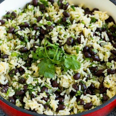 **Rezept für Schwarze Bohnen und Reis** 2 Schwarze Bohnen und Reis in einem Topf, garniert mit Korianderzweigen.