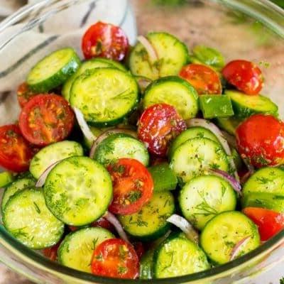 Gurken-Tomaten-Salat 7 Eine Schüssel Gurken-Tomaten-Salat, garniert mit frischen Kräutern.
