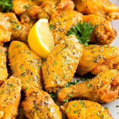Zitronenpfeffer-Flügel 7 Eine Platte mit Zitronen-Pfeffer-Hähnchenflügeln, garniert mit Petersilie und Zitrone.