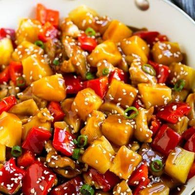 Ananas-Hähnchen 2 Ananas-Hähnchen Stir Fry in einer Pfanne, mit Soße, Sesamsamen und Frühlingszwiebeln garniert.