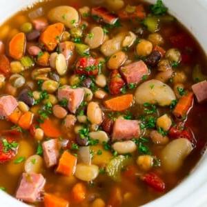 18 Schinkenreste-Rezepte 7 Ein Slow Cooker voller Schinken-Bohnen-Suppe, zubereitet mit Gemüse, getrockneten Bohnen und gewürfeltem Schinken.