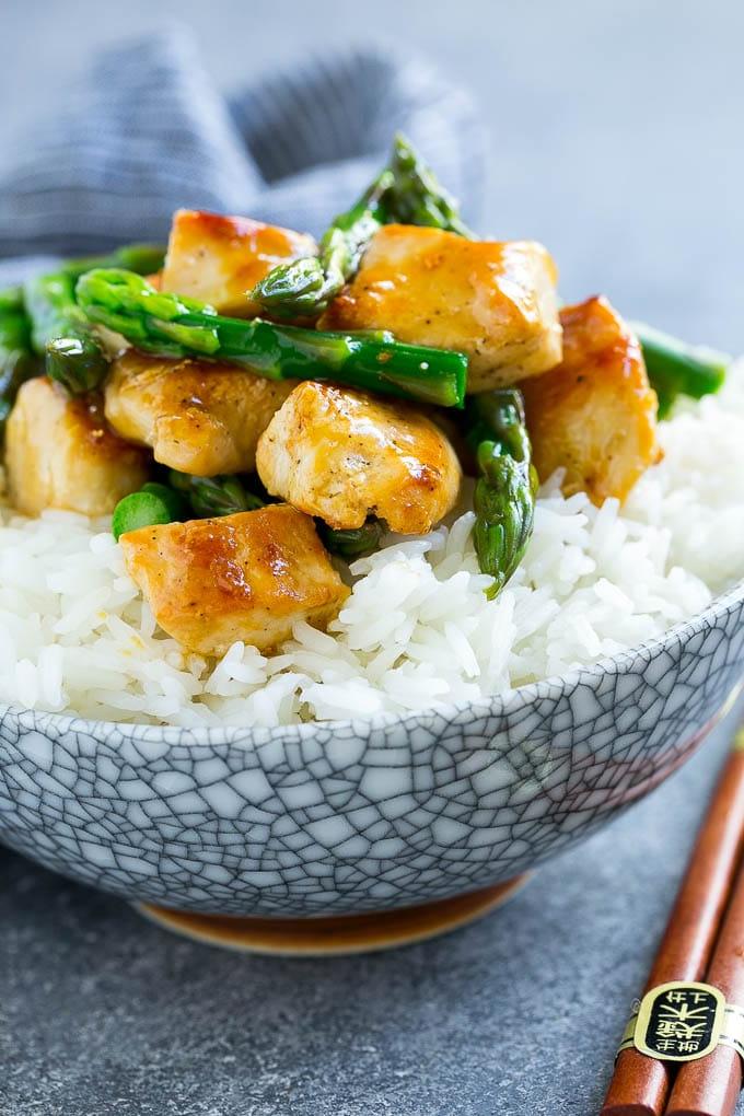 Eine Schüssel mit Hähnchen-Spargel-Wok, serviert über gedämpftem Reis.