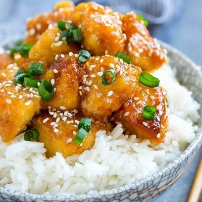 Schongarer Orangenhähnchen 2 Orangen-Hähnchen aus dem Slow Cooker, serviert über einer Schüssel Reis.