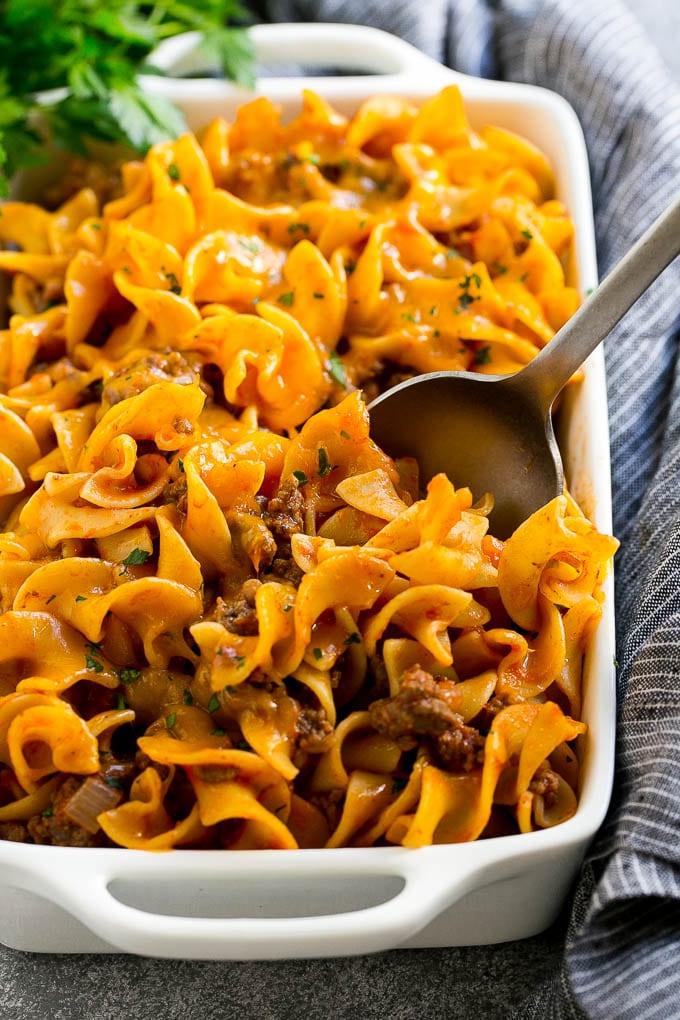 Eine Pfanne mit Hackfleisch-Nudel-Auflauf und einem Servierlöffel darin.