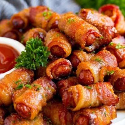 **Würstchen im Speckmantel** 7 Eine Servierplatte mit Bacon Wrapped Smokies, garniert mit Petersilie und einer Beilage Ketchup.