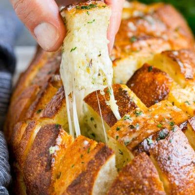 Käsiges Zupfbrot 2 Eine Hand nimmt ein Stück Zupfbrot.