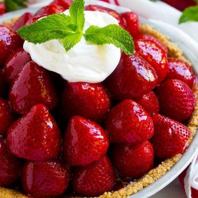 Frischer Erdbeerkuchen 3 Ein Haufen Erdbeeren in einem Graham Cracker Kuchenboden, bedeckt mit einer glänzenden roten Glasur, Schlagsahne und Minze.