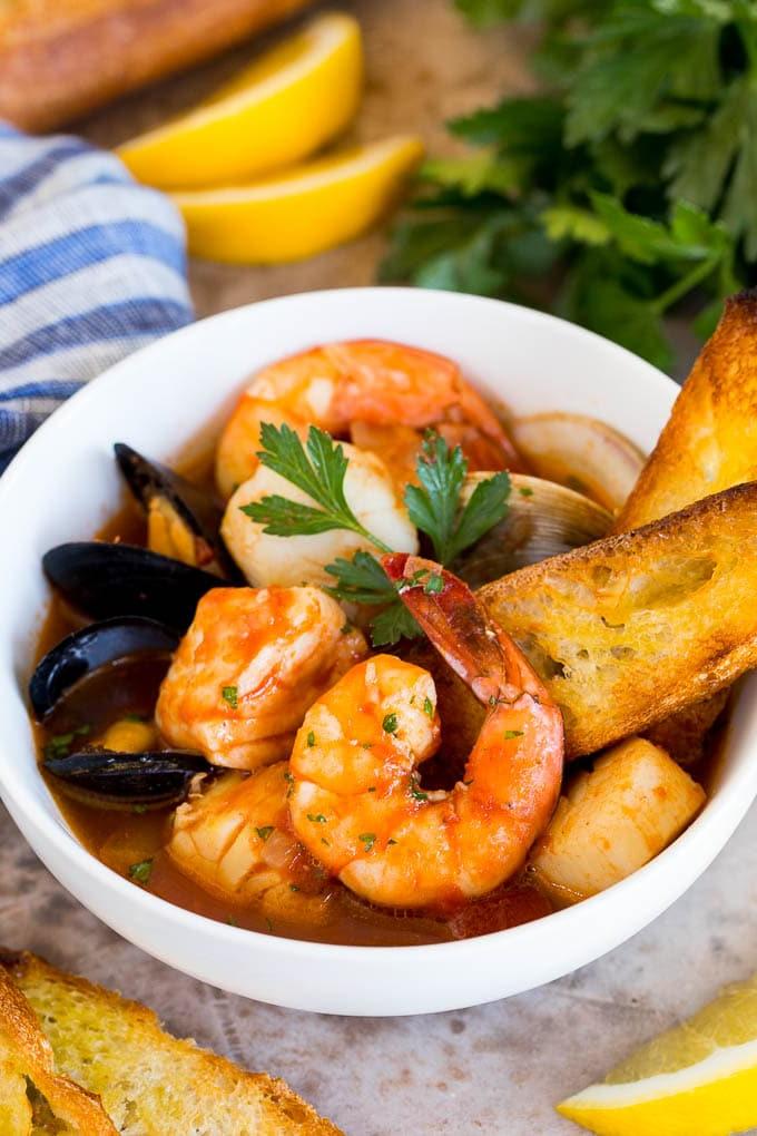 Eine elegante Servierschüssel mit frisch zubereitetem Cioppino, garniert mit gegrillten Brotscheiben, die bereit sind, die köstliche Brühe aufzusaugen.