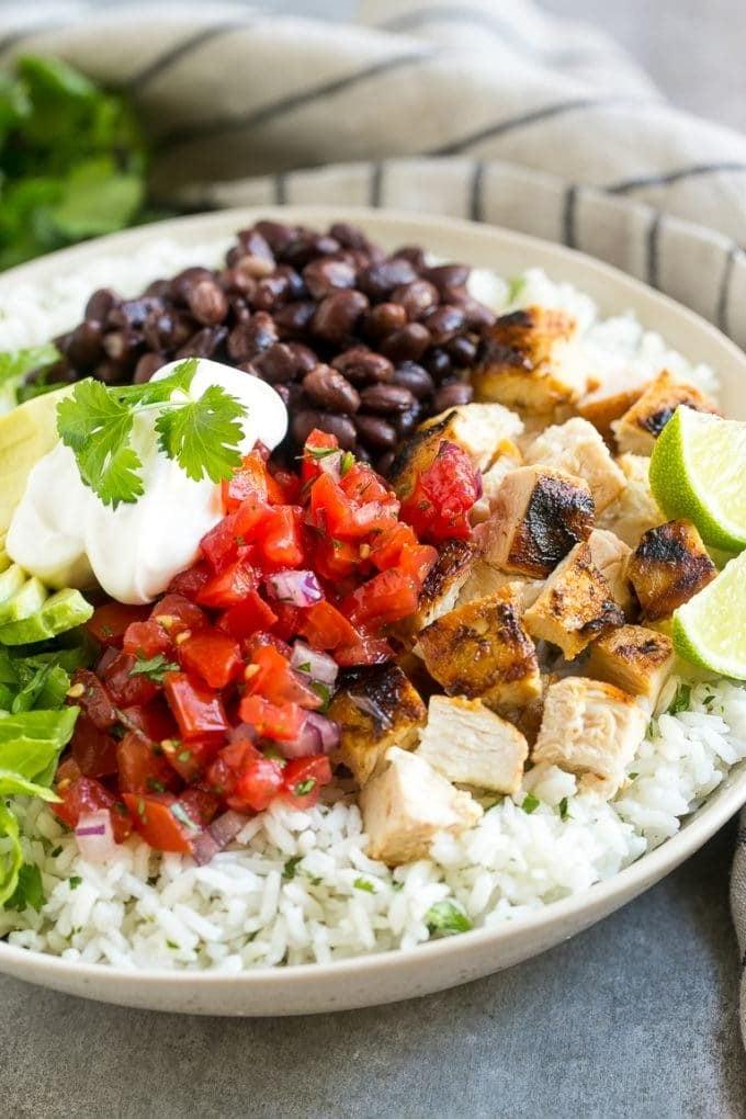 Eine Burrito Bowl mit einer farbenfrohen Auswahl an Toppings, darunter Hähnchen, Bohnen, Salat und frische Salsa.