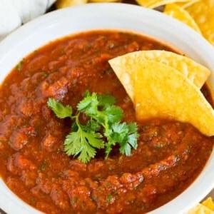 Eine Schale Chipotle-Salsa, garniert mit frischem Koriander und Tortilla-Chips.