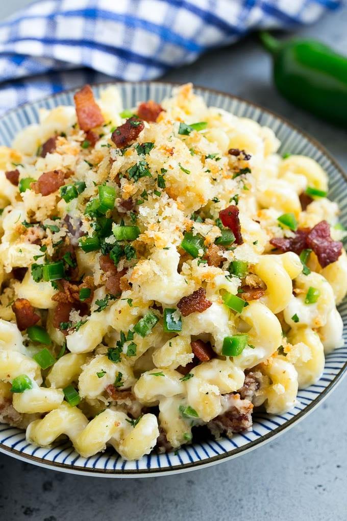 Eine Schale mit Jalapeño Popper Mac and Cheese, belegt mit knusprigen Semmelbröseln, Bacon und Jalapeño-Paprika.