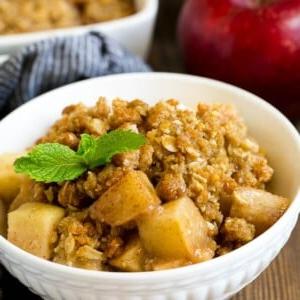 Eine Schüssel Apfel-Crumble garniert mit einem Minzzweig.