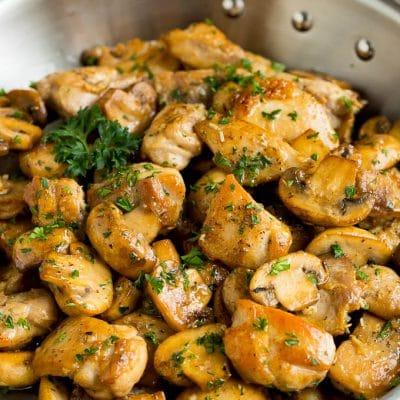 Knoblauchbutter-Hähnchen und Pilze 2 Knoblauch-Butter-Hähnchen und Champignons, mit Petersilie garniert und servierfertig.