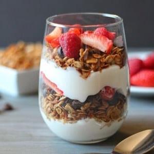Ein Bild von Granola-Joghurt-Parfait mit Beeren in einem klaren Glas.